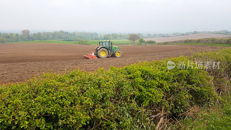 Typically British, a tractor ploughing a field in the English countryside, preparing the soil for planting crops, agriculture at its best .